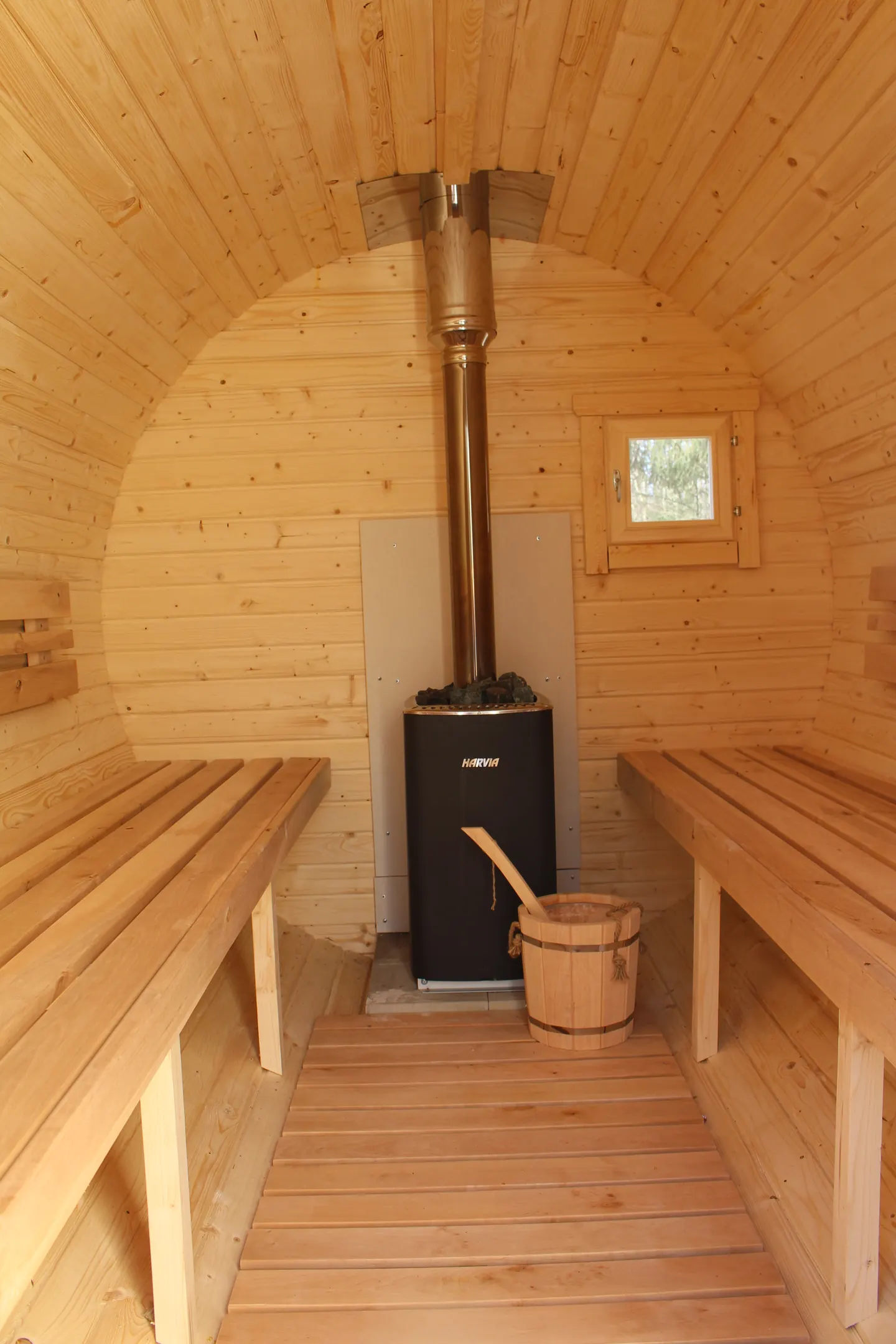 Innenraum der Fass-Sauna mit Holzofen und Sitzbänken